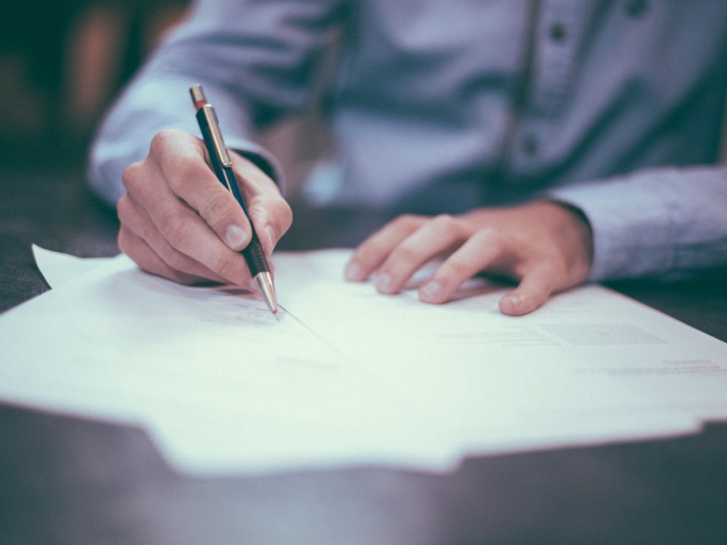 Vendedor firmando la escritura de compraventa de una vivienda, responsable de pagar la plusvalía municipal