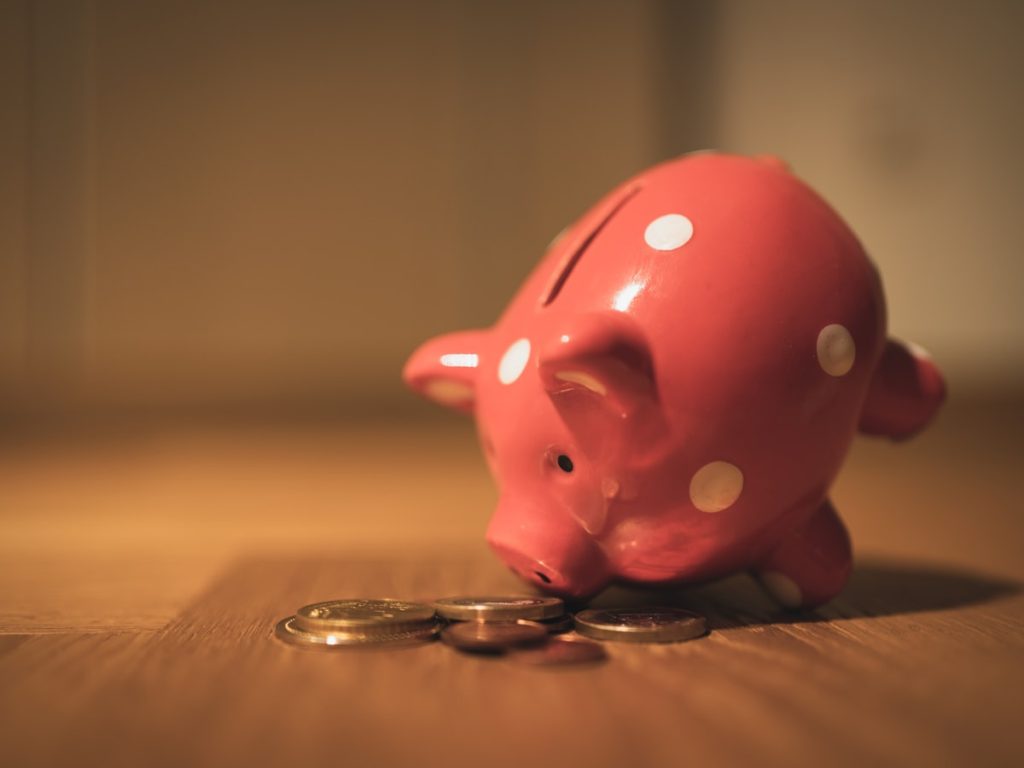 Hucha y monedas que representan la renta estable que genera un piso alquilado