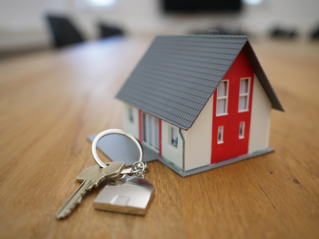 Llaves y maqueta de una casa sobre una mesa que representan la venta de una vivienda hipotecada