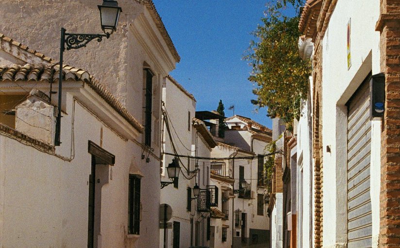 Calle tradicional andaluza con fachadas encaladas y farolas de forja